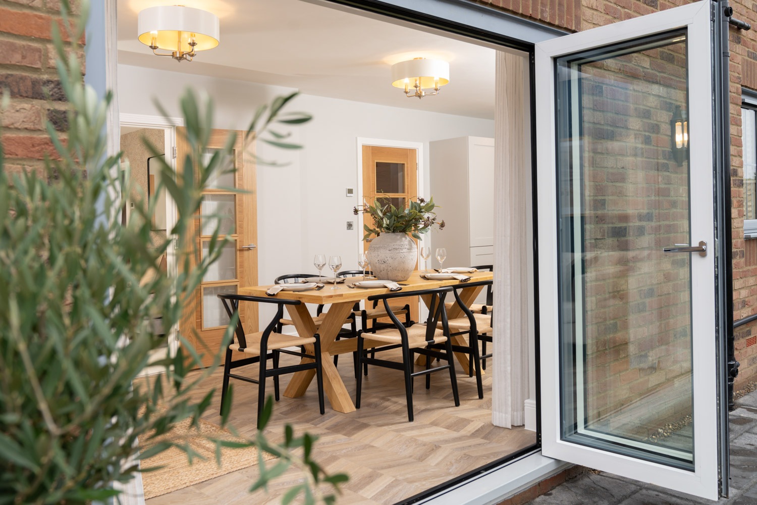 Open doors look into dining area with dining table and chairs and wooden flooring
